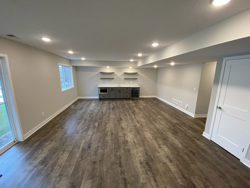 After picture of a clean, finished basement project with hardwood floors and a home bar in Southeast metro, MN.